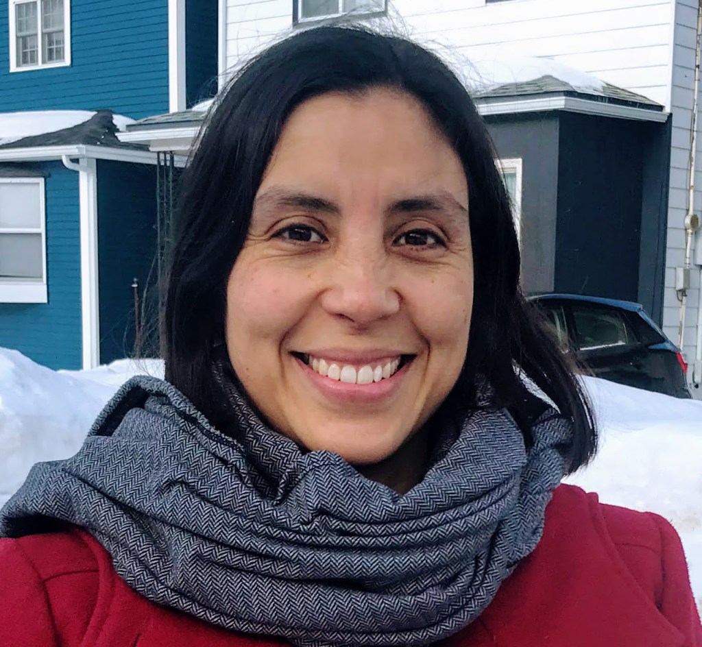 Photo of Viviana smiling. She has dark long hair, brown eyes and brown skin